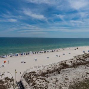 Gaze at the inviting shoreline, where colorful umbrellas dot the beach and guests enjoy the warm sun and gentle waves