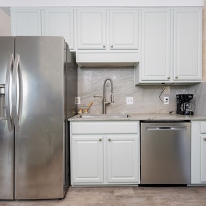 Bright and airy kitchen featuring stainless appliances, sleek countertops, and a cozy view of the inviting guest bedroom
