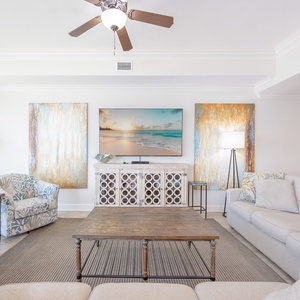 Living space featuring a large TV, cozy seating, and a view into the modern kitchen area
