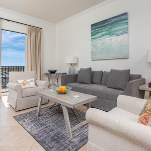 Cozy seating area features a gray sofa with queen sleeper, two armchairs, and a coffee table adorned with fresh fruit