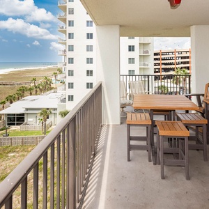 Balcony with wooden seating offers a relaxing spot to enjoy views of the beach and lush greenery below