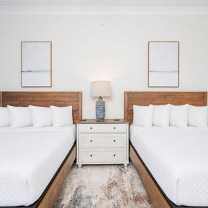Serene guest bedroom featuring two queen beds, stylish decor, and large windows with beach views