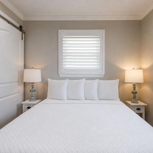 This bedroom features a cozy bed with fluffy pillows, soft lighting from stylish lamps, and a clean, inviting atmosphere