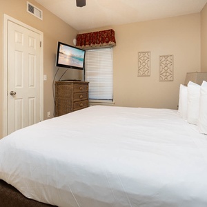 Relax in the spacious master featuring a king bed, a mounted TV, and tasteful decor for a restful stay