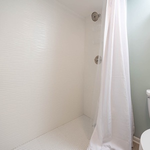 Refreshing walk-in shower with modern fixtures, textured walls, and a serene atmosphere for your daily routine