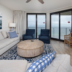 Unwind in the stylish living area, featuring a comfortable sofa, accent chairs, and a beachfront balcony view