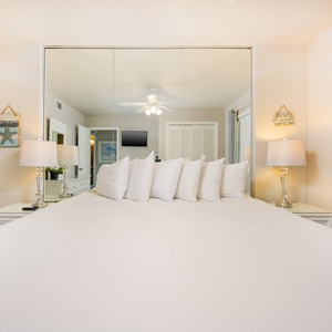 This bedroom features a large white bed with plush pillows, a TV, and soft lighting for a relaxing stay