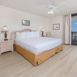 Master suite featuring a king bed, coastal decor, and a balcony with views of the tranquil gulf waters