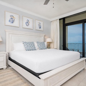 Elegant master suite, featuring a king bed, decorative pillows, and beachfront balcony access