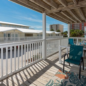 This inviting balcony features teal chairs and a table, perfect for enjoying a relaxing view of the surrounding area