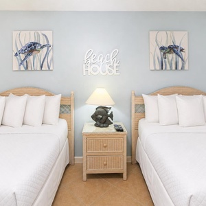 Rest in this guest bedroom with double beds, beach decor, and a charming lamp with soft lighting