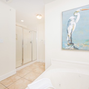 Luminous master bathroom featuring a jetted tub, walk-in shower, and a serene bird painting on the wall