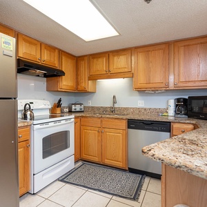 The kitchen features warm wooden cabinetry, granite countertops, and essential appliances for a convenient cooking experience