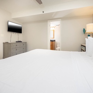 This cozy bedroom features a large king bed, a mounted TV, and an inviting atmosphere with soft lighting