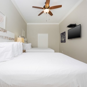 Relax in this inviting guest bedroom featuring two queen beds, a TV, and soft decor for a restful stay