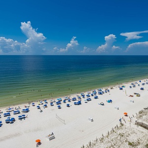 Vibrant beach scene, where colorful umbrellas and guests enjoy the warm waters and sunlit shoreline