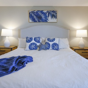 Decorous blue accents complement the white bedding in this serene master suite, featuring stylish nightstands and lighting