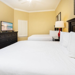 Guest bedroom featuring two comfortable queen beds, a flat-screen TV, and warm yellow walls for a relaxing stay