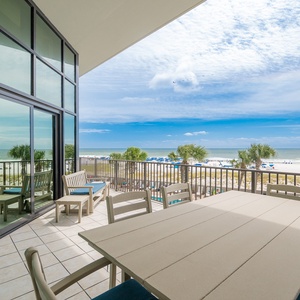 Spacious balcony with comfortable seating and breathtaking views of the pristine beach and vibrant blue skies