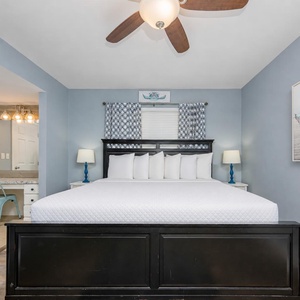 The master bedroom features a king bed with white linens, blue accents, and a cozy vanity area, perfect for relaxation