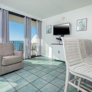 This inviting living room features a comfortable chair and a stunning beachfront view through large windows