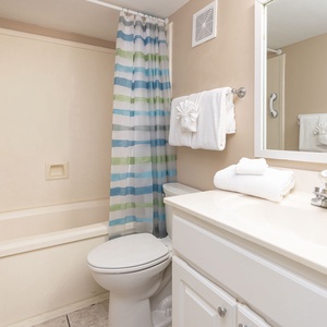 Guest bathroom featuring a tub/shower combo, fresh towels, and a stylish striped shower curtain