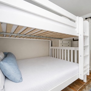 Queen over queen bunk bed with soft linens and a blue accent pillow, perfect for a restful sleep in a charming guest room