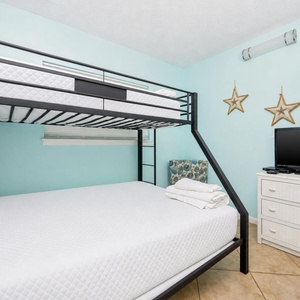 This guest room features a bunk bed, a comfortable double bed, and a TV, perfect for family or friends to relax together