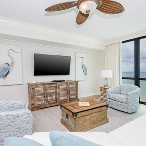 Relax in the cozy seating area, featuring beach-themed decor and a view of the tranquil waters through large windows