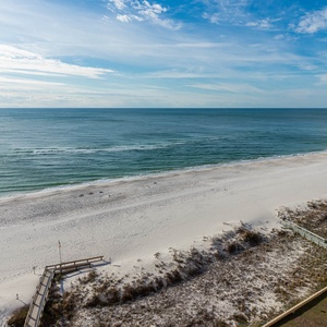 Expansive view of the beach with soft white sand and gentle waves, inviting relaxation and seaside strolls