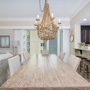 Gather around the rustic dining table under a unique chandelier, with views of the beach through large windows
