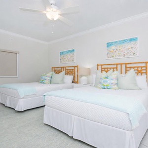 Cheerful guest bedroom featuring two queen beds with vibrant pillows and playful art
