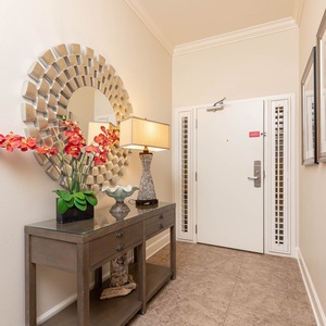 This welcoming entryway features a stylish console table, floral decor, and a decorative mirror, setting a cheerful tone