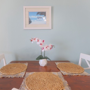 This dining area features a wooden table set with woven placemats and a decorative orchid, perfect for meals with loved ones