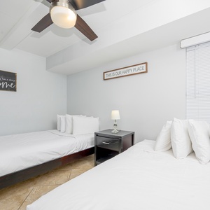 This inviting room features two comfortable beds, soft linens, and a warm welcome sign for a relaxing stay