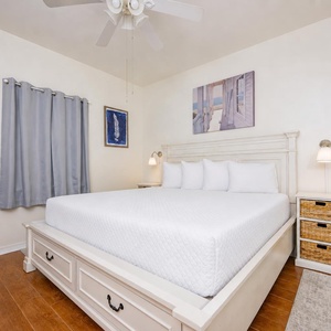 King bed in the master suite welcomes you to unwind beneath the ceiling fan's gentle hum and soft lamp glow