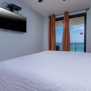 Relax in this cozy master bedroom with a large king bed, a TV, and beautiful beach views with balcony access