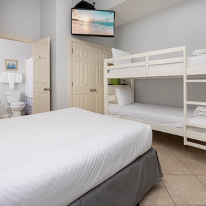 The guest room features a double bed, twin bed, twin bunk bed, and TV mounted above, creating a cozy space for families