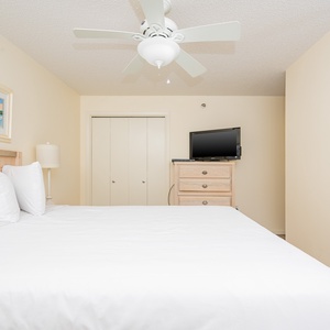 Inviting guest bedroom featuring a queen bed, TV, and coastal artwork for a serene retreat