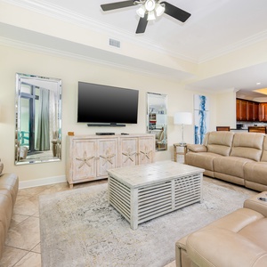 This cozy living area features a large TV, stylish decor, and a view of the inviting kitchen with rich wood cabinetry