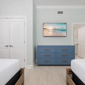 Inviting bedroom featuring two cozy queen beds, a blue dresser, and a TV for entertainment