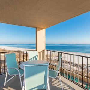 Enjoy relaxing moments on the balcony with turquoise chairs and a table, overlooking the serene beach view