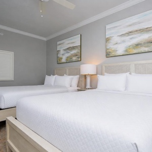Inviting guest room featuring two cozy queen beds, soft lighting, and calming artwork