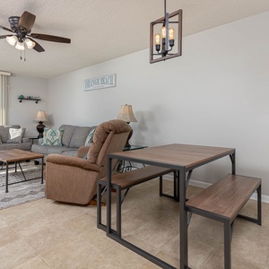 Cozy living area features two sofas, a queen aleeper, wooden coffee table, and a dining set, all with a beachfront view