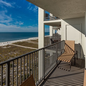 Balcony with two chairs offers a serene view of the beach and gulf, perfect for relaxing and enjoying the coastal breeze