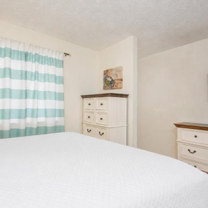 Relax in the plush queen bed, enjoying serene moments with coastal artwork and cozy vibes in the master suite