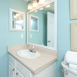 The guest bath features a light blue color scheme, a spacious vanity with a sink, and fresh white towels for your convenience