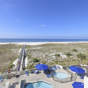 Gulf view from the balcony showcases a serene beach path leading to the shore, with inviting lounge areas by the pool
