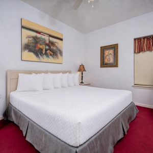 This inviting bedroom features a king bed with plush white linens, complemented by elegant artwork and a TV on the dresser