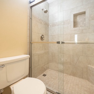 The master bathroom features a glass-enclosed walk-in shower with elegant tile work and a refreshing modern vibe